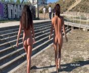 Two girlfriends walk naked on a public beach from nudist beach